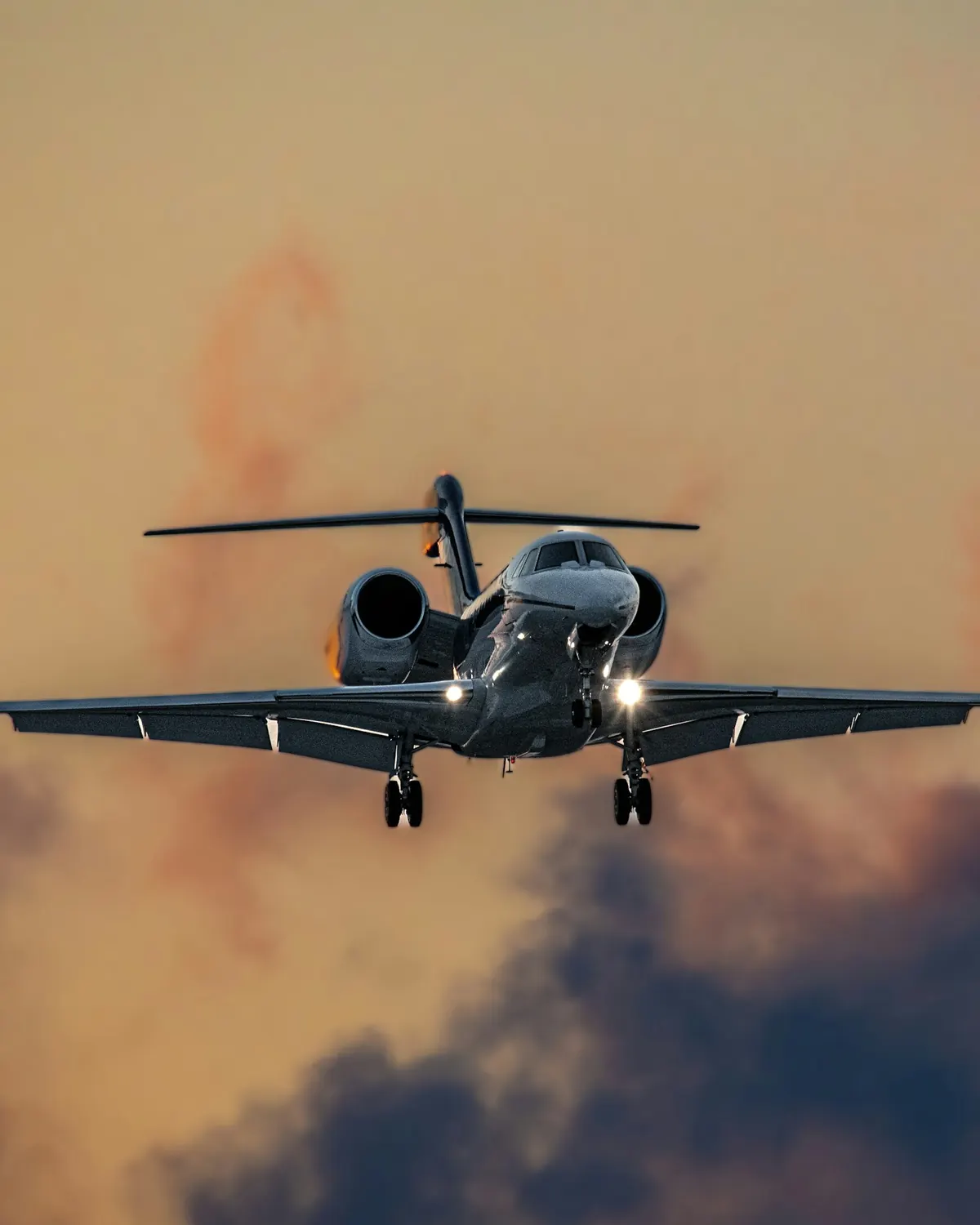A business jet descending through clouds toward the runway