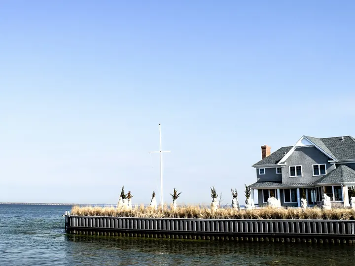 A shingled waterfront house beside its pier