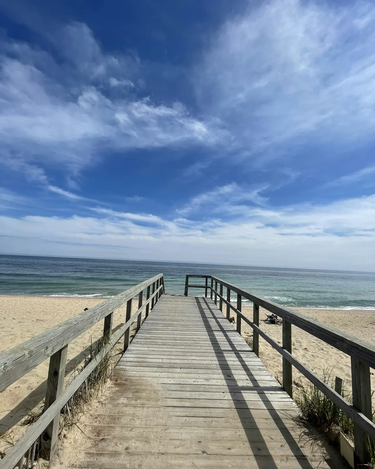 A wooden boardwalk leading over the dunes to the beach